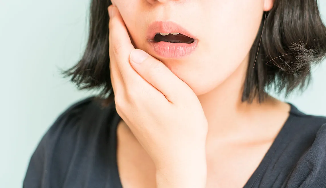 歯が痛く頬を抑えている女性